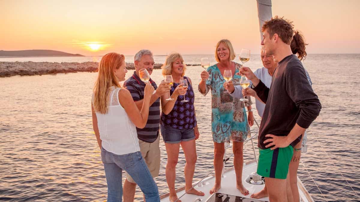 Group enjoy a sunset drink together on their yacht