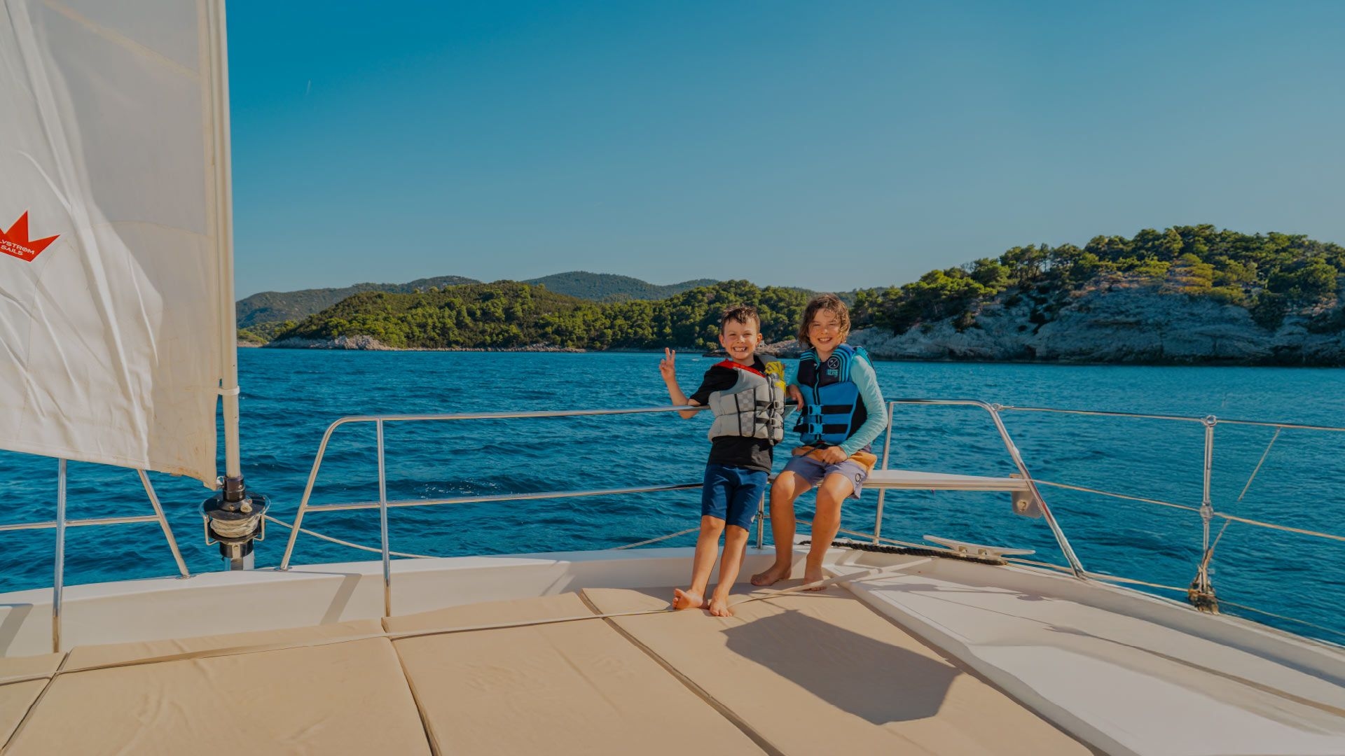 Two kids on the bow of a catamaran in Croatia